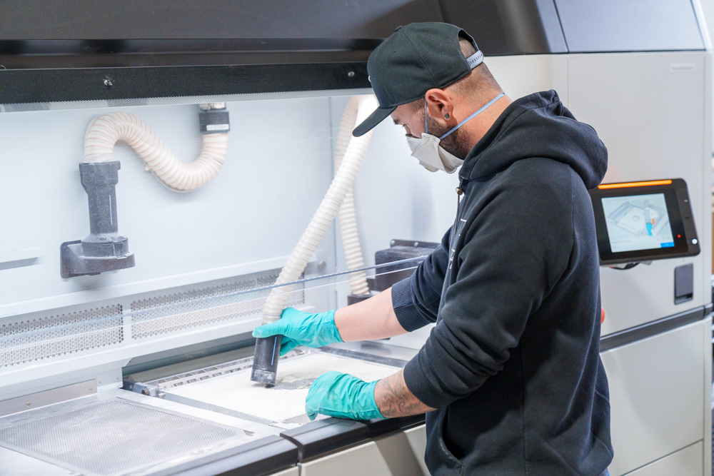 Industrieller 3D-Druck – Mitarbeiter bei KIT3D arbeitet an einer HP Multi Jet Fusion Anlage in der industriellen Fertigung