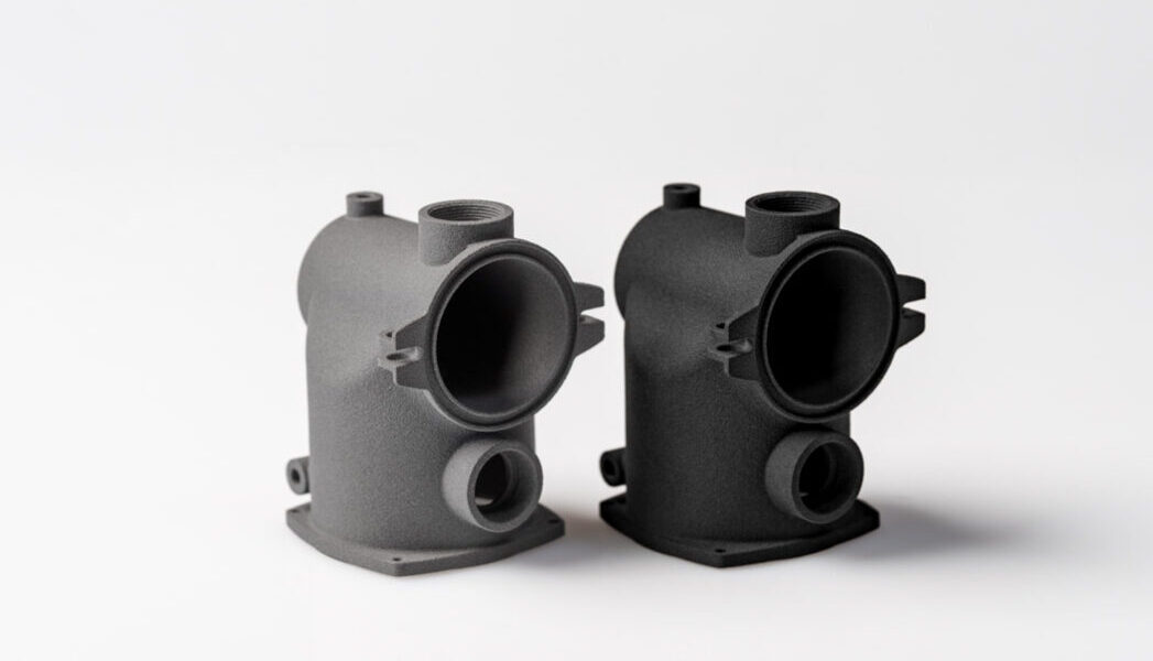 Zwei industrielle 3D-Druck Farbfinishing aus SLS und MJF nebeneinander, ein Bauteil grau, eines schwarz, mit identischer Geometrie zur Darstellung von Material- und Farbunterschieden.