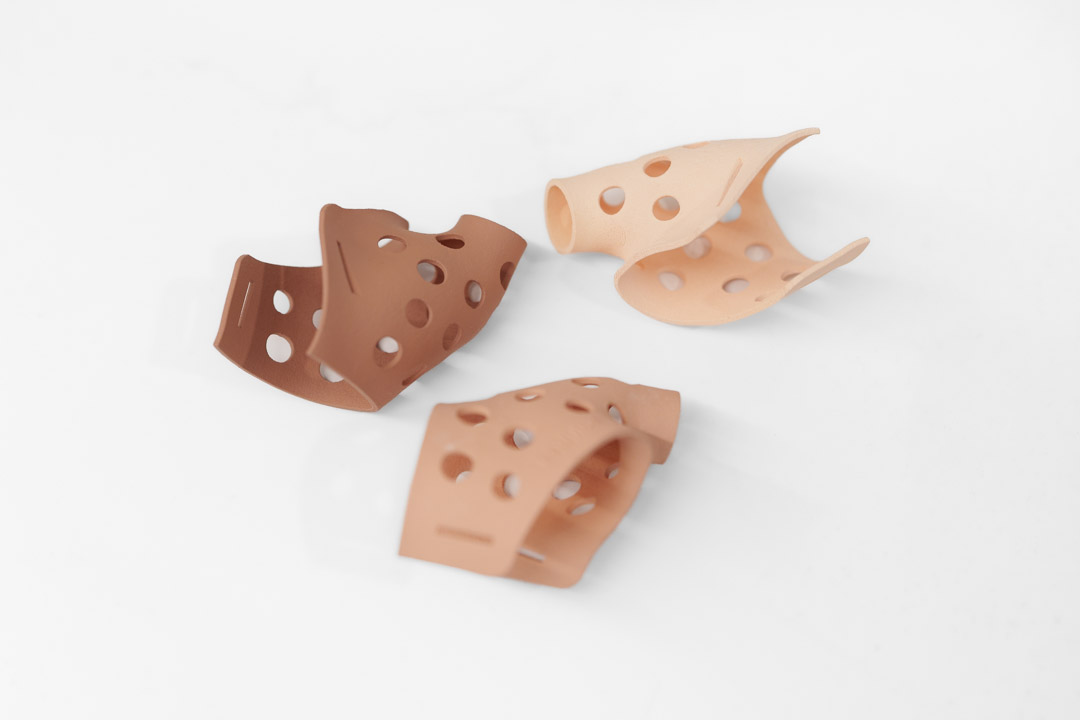 3d druck farbfinishing an gebogenen 3D-gedruckten Kunststoffmustern in verschiedenen Hautfarbtönen mit Lochstruktur auf weißem Hintergrund