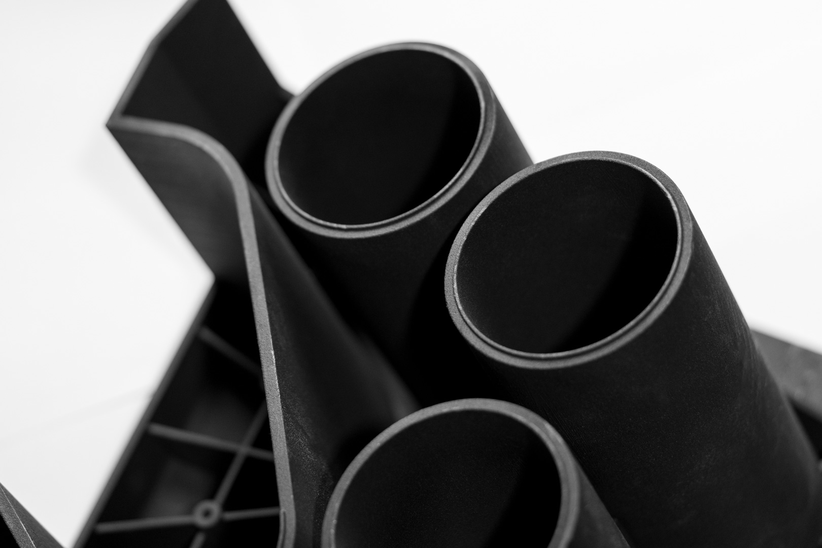 Industrielles 3D-gedrucktes Kunststoffbauteil mit mehreren zylindrischen Aufnahmen und komplexer Geometrie als Beispiel moderner Technologien in der additiven Fertigung.