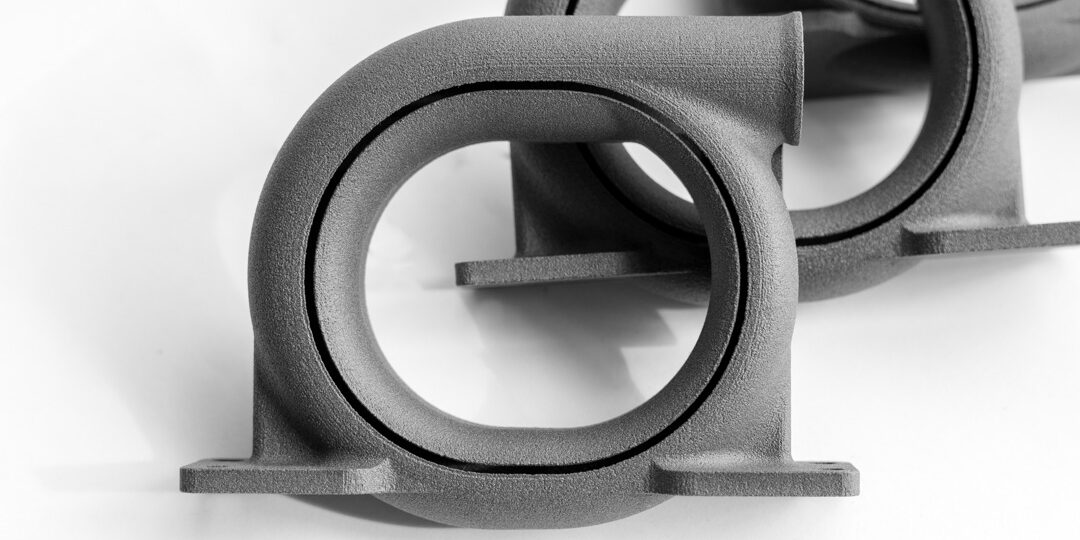 Graue 3D-gedruckte Gehäusebauteile mit runden Öffnungen und strukturierter Oberfläche auf weißem Hintergrund.
