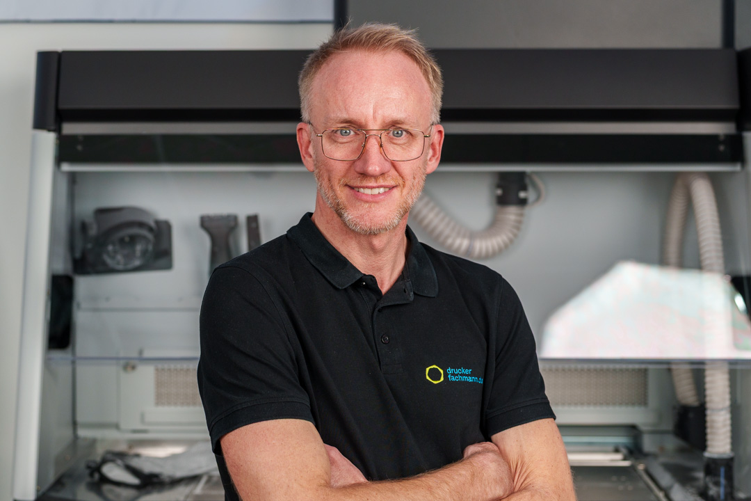 Dennis Opielka vor industrieller 3D-Drucktechnik im Bereich 3D Druck Orthopädietechnik.