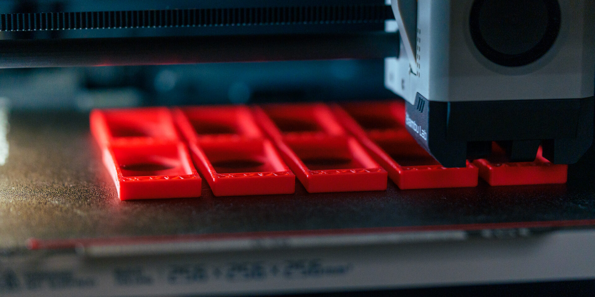 FDM 3D-Druck Service beim Fertigen roter Bauteile auf dem Druckbett eines 3D-Druckers.