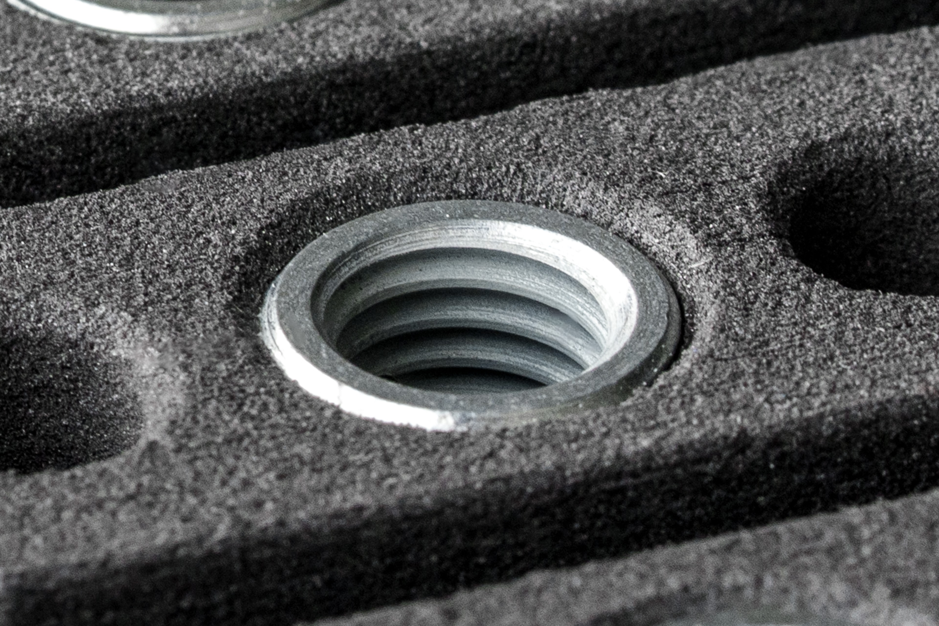 Detailaufnahme einer eingesetzten Eindrehbuchse in einem naturgrauen SLS-Bauteil aus PA12