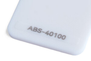 ABS 40100 - KIT3D GmbH – 3D-Technologie & Konstruktion Close-up of a white plastic surface with the model number ABS-40100 embossed near the corner from a diagonal angle.