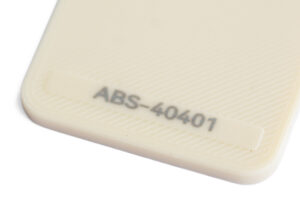 ABS 40401 - KIT3D GmbH – 3D-Technologie & Konstruktion Close-up of a pale beige plastic surface with diagonal grooves and the label 'ABS-40401' embossed near a rounded corner.