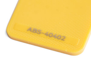 ABS 40402 - KIT3D GmbH – 3D-Technologie & Konstruktion Close-up of a yellow plastic surface with the text 'ABS-40402' embossed and fine diagonal texture lines.