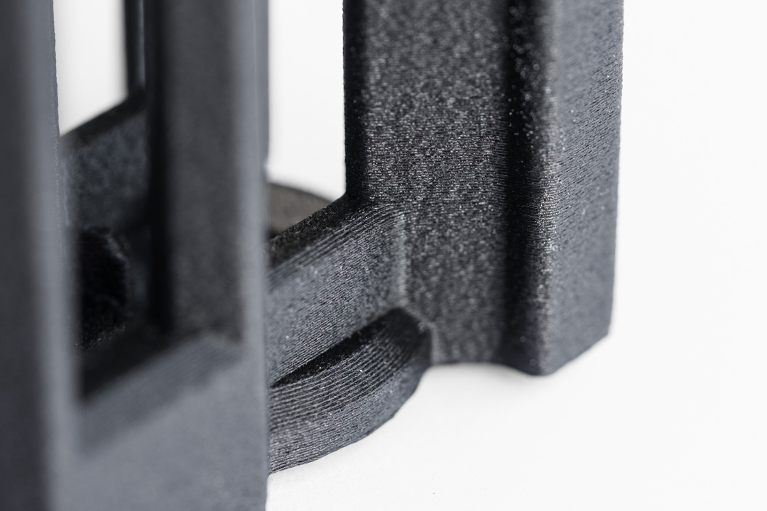 Detailaufnahme eines schwarzen FDM-3D-Druckbauteils mit sichtbarer Schichtstruktur