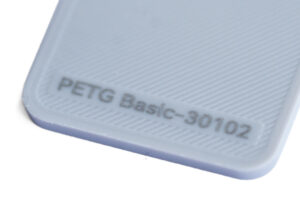 PETG Basic 30102 - KIT3D GmbH – 3D-Technologie & Konstruktion Close-up of a light-blue PETG Basic-30102 plastic edge with a ridged texture and engraved text.