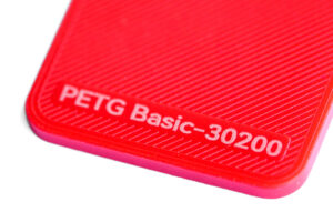 PETG Basic 30200 - KIT3D GmbH – 3D-Technologie & Konstruktion Red plastic close-up with embossed label reading 'PETG Basic-30200'.