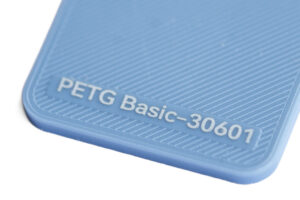 PETG Basic 30601 - KIT3D GmbH – 3D-Technologie & Konstruktion Close-up of a blue plastic piece with the embossed text 'PETG Basic-30601' along a textured edge.