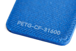 PETG CF 31600 - KIT3D GmbH – 3D-Technologie & Konstruktion Close-up of a blue textured plastic piece with the text PETG-CF-31600 inscribed on it.","Blue 3D-printed part edge showing engraved code PETG-CF-31600.","Corner of a blue plastic component with the label PETG-CF-31600.","Macro shot of a blue object bearing the code PETG-CF-31600.","Blue plastic part with the model/code PETG-CF-31600 visible on the surface."