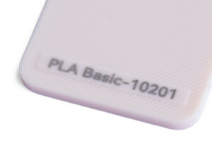 PLA 10201 - KIT3D GmbH – 3D-Technologie & Konstruktion Close-up of a pale pink plastic object with an embossed label reading PLA Basic-10201 at the corner.