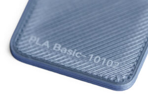 PLA Basic 10102 - KIT3D GmbH – 3D-Technologie & Konstruktion Close-up of a blue textured 3D-printed surface with the label 'PLA Basic-10102'.