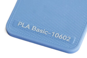 PLA Basic 10602 - KIT3D GmbH – 3D-Technologie & Konstruktion Close-up of a blue textured plastic surface with a label reading 'PLA Basic-10602'.