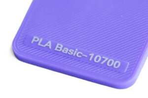 PLA Basic 10700 - KIT3D GmbH – 3D-Technologie & Konstruktion Purple textured plastic surface with diagonal ridges and an embossed badge reading 'PLA Basic-10700'.