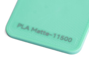 PLA Matte 11500 - KIT3D GmbH – 3D-Technologie & Konstruktion Mint-green surface with the text 'PLA Matte-11500' near a rounded corner on a plastic edge.