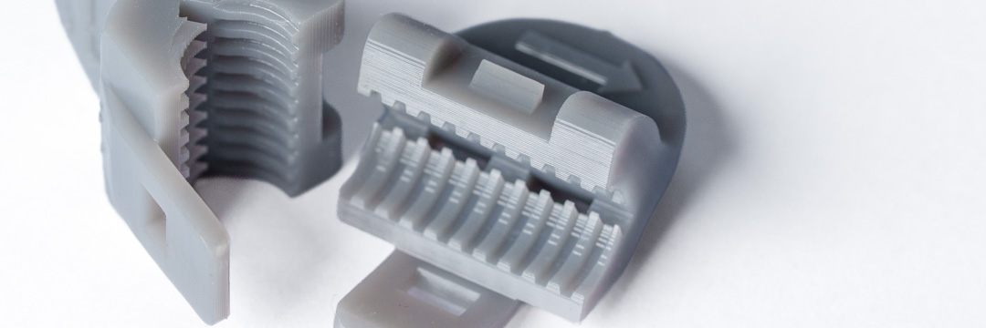 Graue SLA-3D-Druckbauteile mit feinen Gewinden, filigranen Strukturen und hoher Detailgenauigkeit